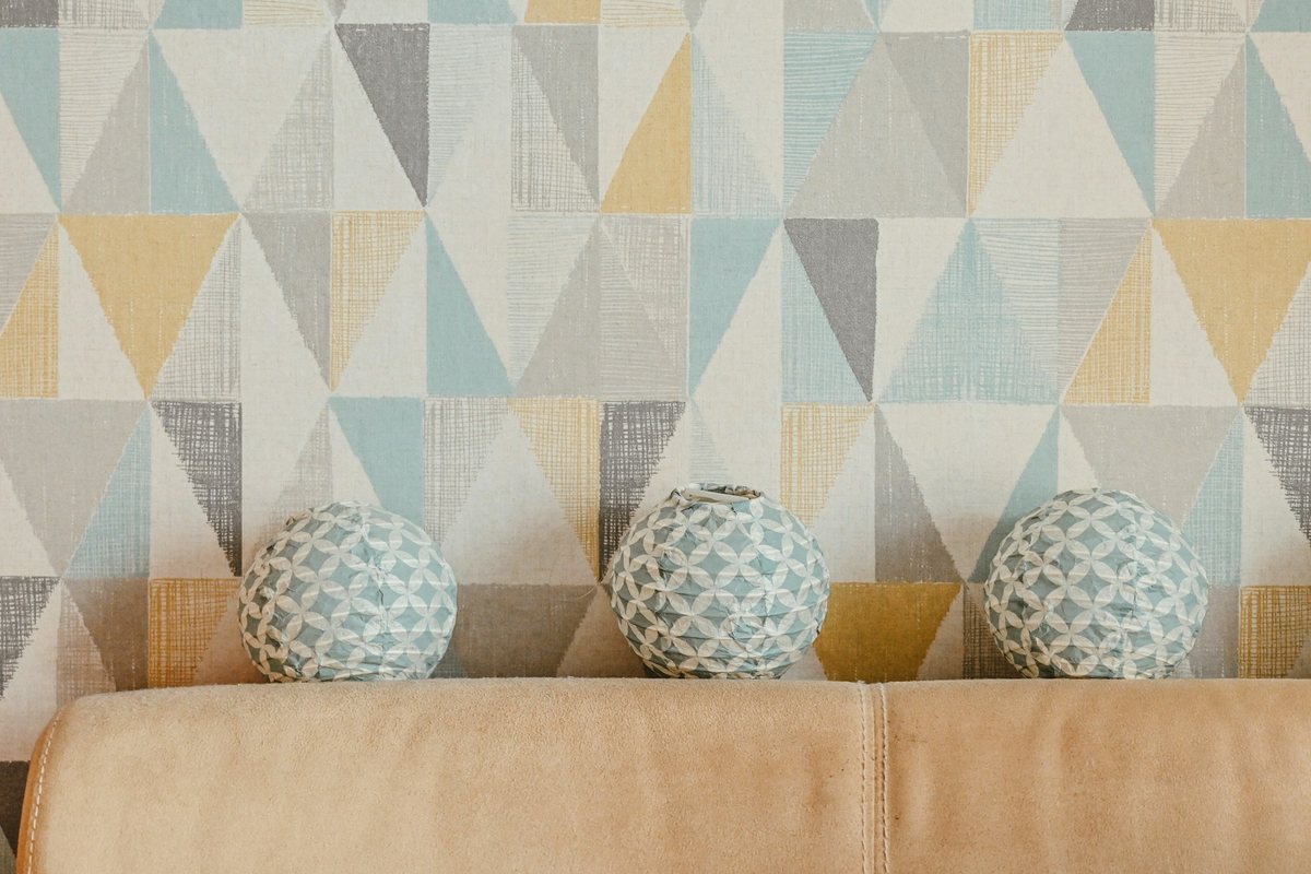 Pastel triangle-patterned wallpaper above a tan sofa with three patterned decorative spheres